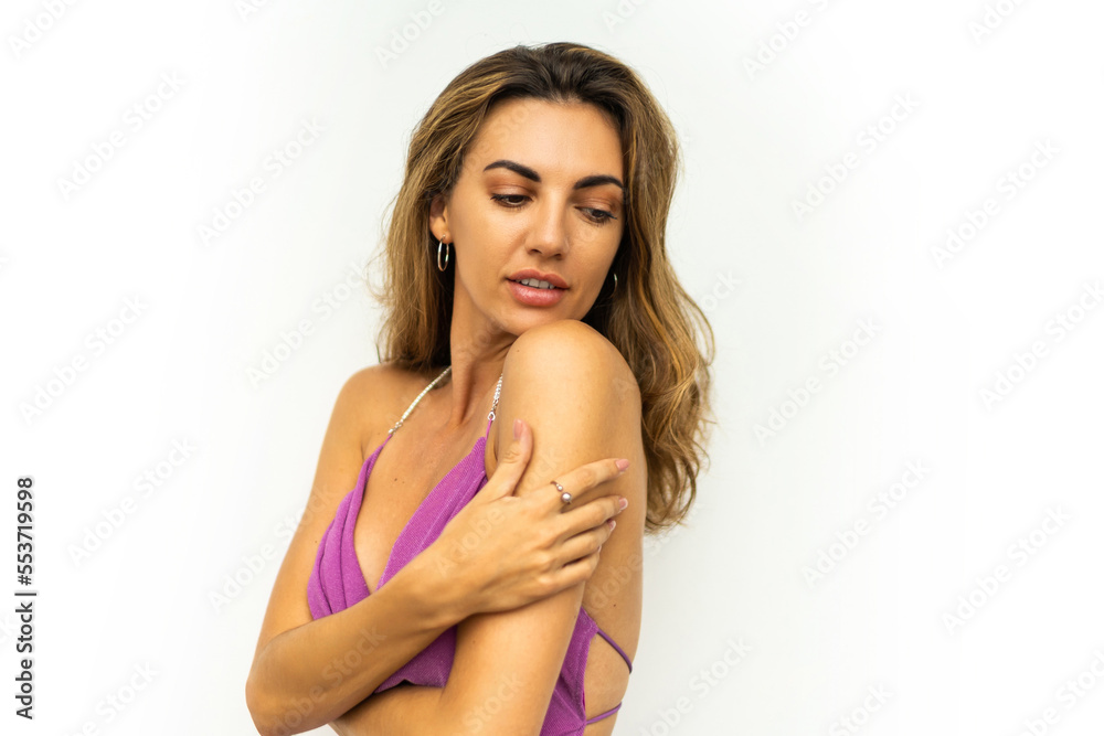 Fototapeta premium Close up portrait of Seductive woman in pink elegant dress posing over white background. Tann perfect skin. Wavy hairs. Full lips.
