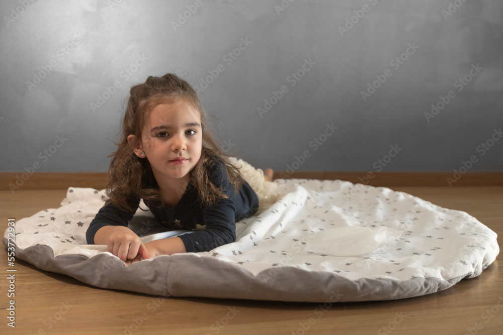 Cute little girl lying on the play mat with calm expression Stock Photo ...