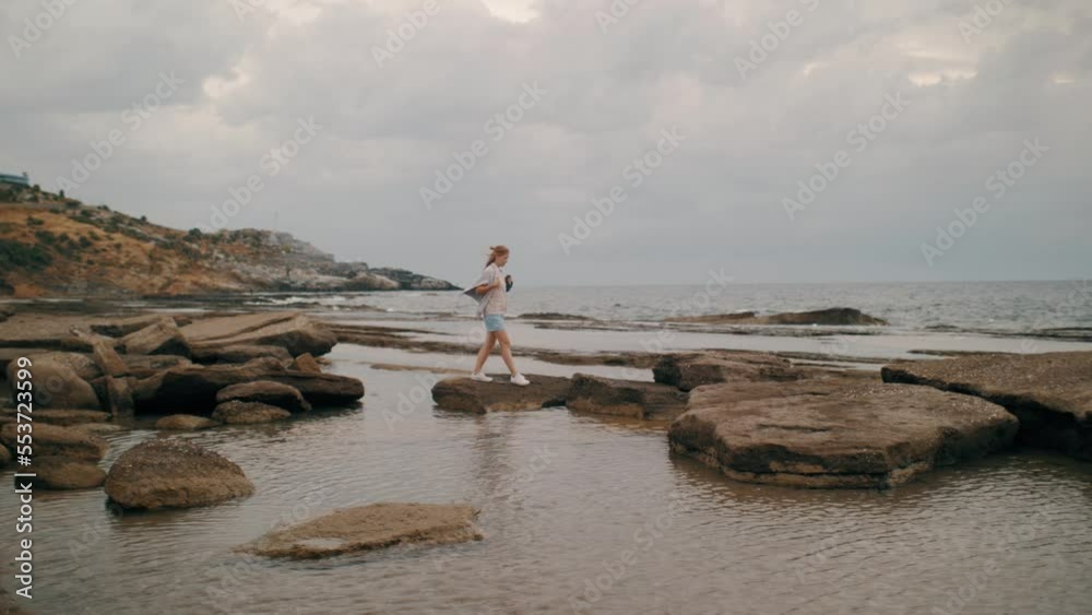 Casual young tourist woman walking sea wave beach jumping stone cliff at water wave slow motion Casual young tourist woman walking sea wave beach jumping stone cliff at water wave slow motion