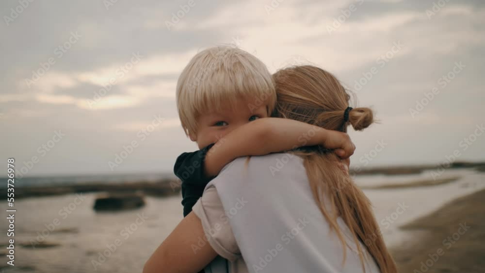 Happy blonde baby boy hugging mother feeling love tenderness at sand beach seaside island closeup Happy blonde baby boy hugging mother feeling love tenderness at sand beach seaside island closeup