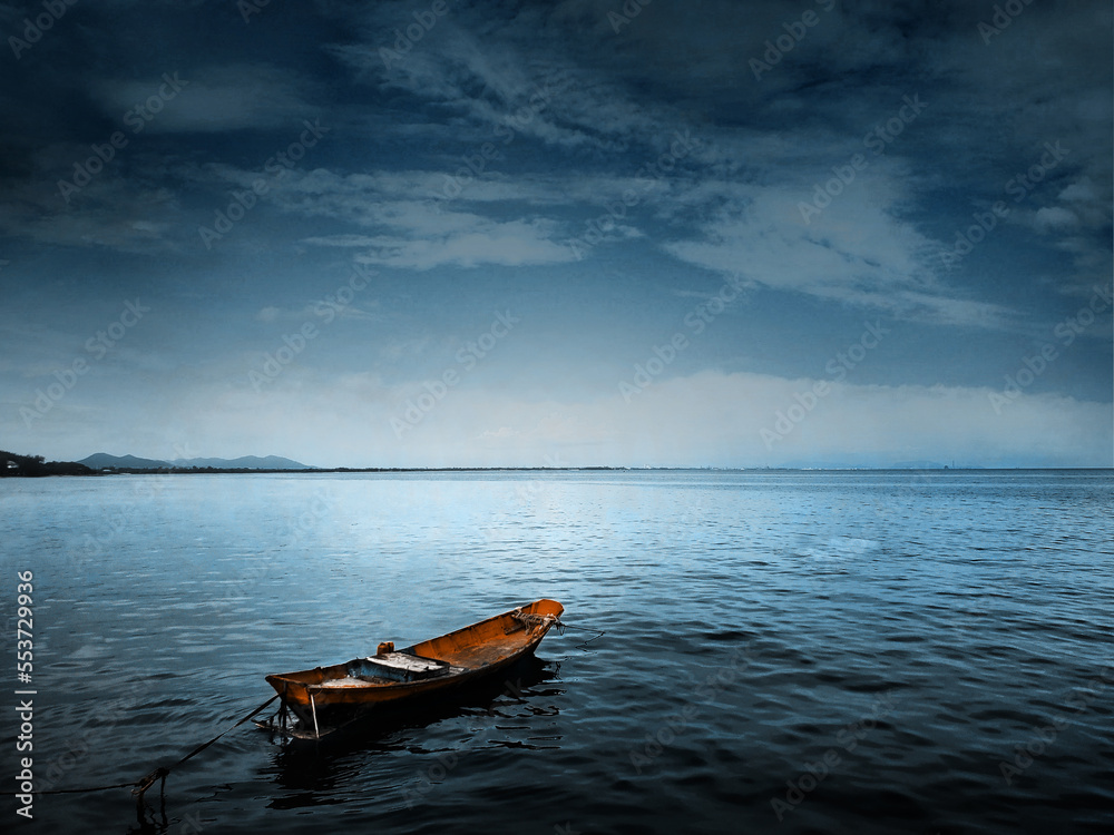 A small fishing boat in the middle of the sea at sunset A small fishing boat in the middle of the sea at sunset