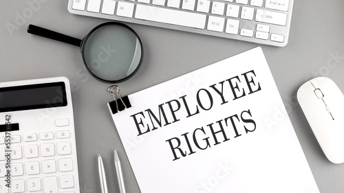 EMPLOYEE RIGHTS written on paper with office tools and keyboard on the grey background