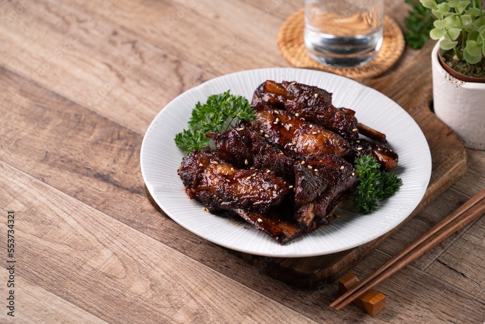Barbecue pork spare ribs in a plate on wooden table background.