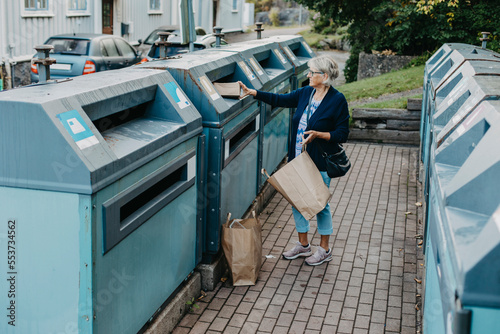 Woman putting cardboard in recycling bin photo