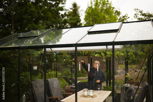 Woman lightning candles in greenhouse photo