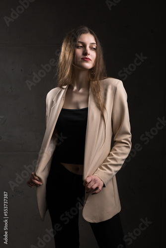 Portrait of a young brunette with long hair in the studio. Dramatic photo in dark colors.