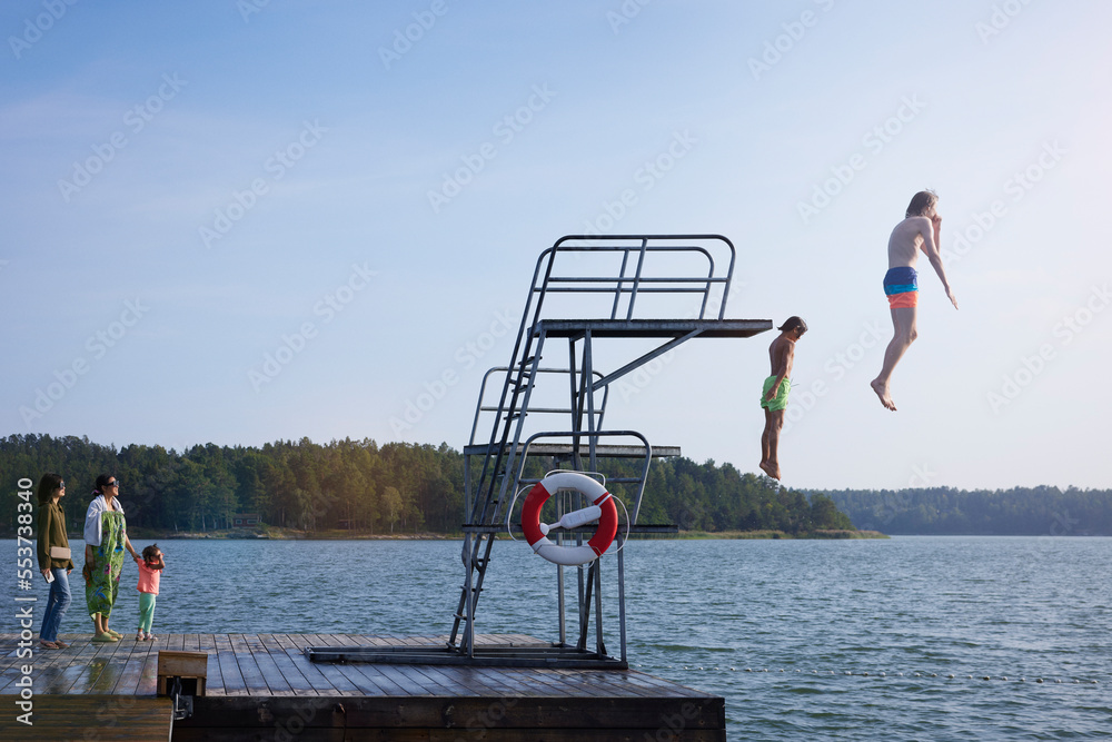 Teenage boys jumping into water from jumping tower Stock Photo | Adobe ...