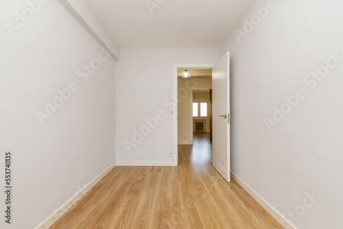 An empty room freshly painted plain white and with small floors of new driftwood flooring