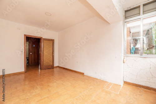 An old and used empty room with tiled floors and enclosed terrace addition