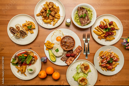A still life with dishes of Peruvian and Ecuadorian gastronomy, chorizo with fried potatoes, a combined plate with rice and avocado, lomo saltado, fillet with green noodles, stuffed potato