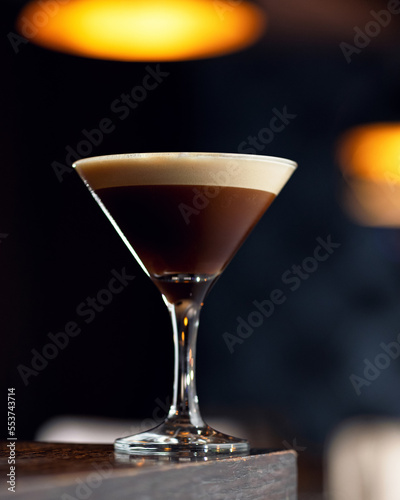Coffee alcoholic cocktail. Alcoholic drink in cocktail glass on wooden table. Blurred background, soft focus. Copy space.