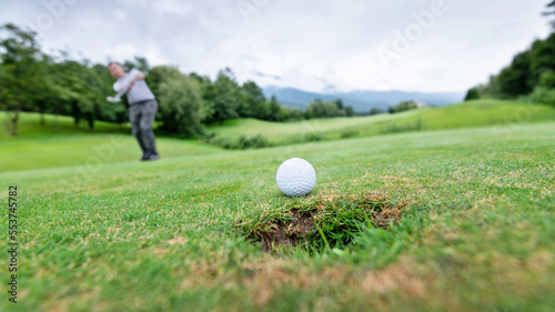 Golfer putting golf ball on the hole