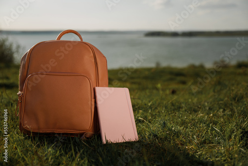 A school bag and a notebook on the grass near the sea