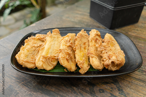 A plate of Indonesian pisang goreng tepung or fried banana snack for breakfast or hang out. Usually served with hot tea or coffee photo