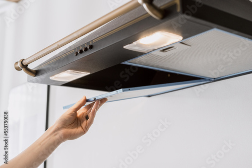 woman installing new hood filter at kitchen