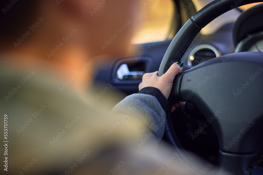 Blurred image of a woman driving a car.