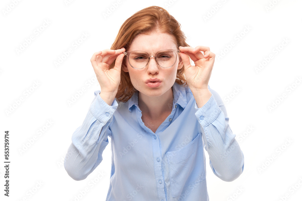 Redhead young woman wearing glasses squinting while looking at camera isolated on white background. Vision problems concept