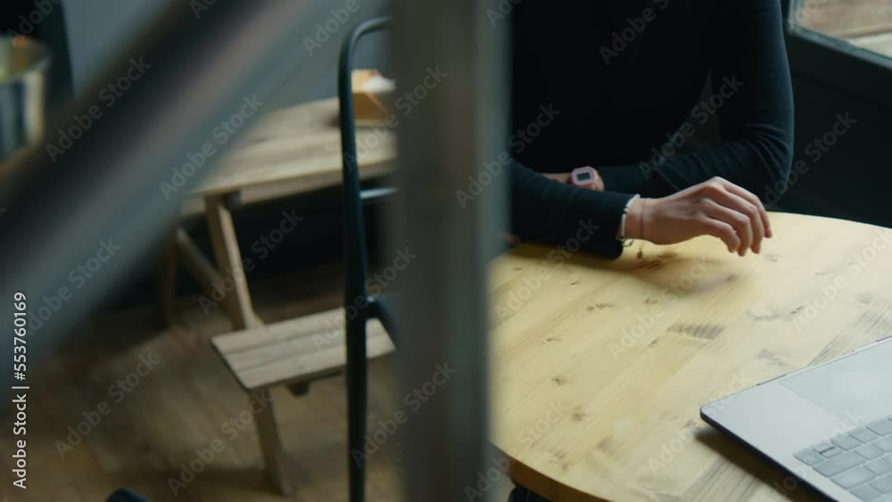 Young business woman work on laptop in specialty coffee shop. Unrecognisable customer at restaurant or cafe, get served lunch by waiter. Customer service in coffeeshop Young business woman work on laptop in specialty coffee shop. Unrecognisable customer at restaurant or cafe, get served lunch by waiter. Customer service in coffeeshop