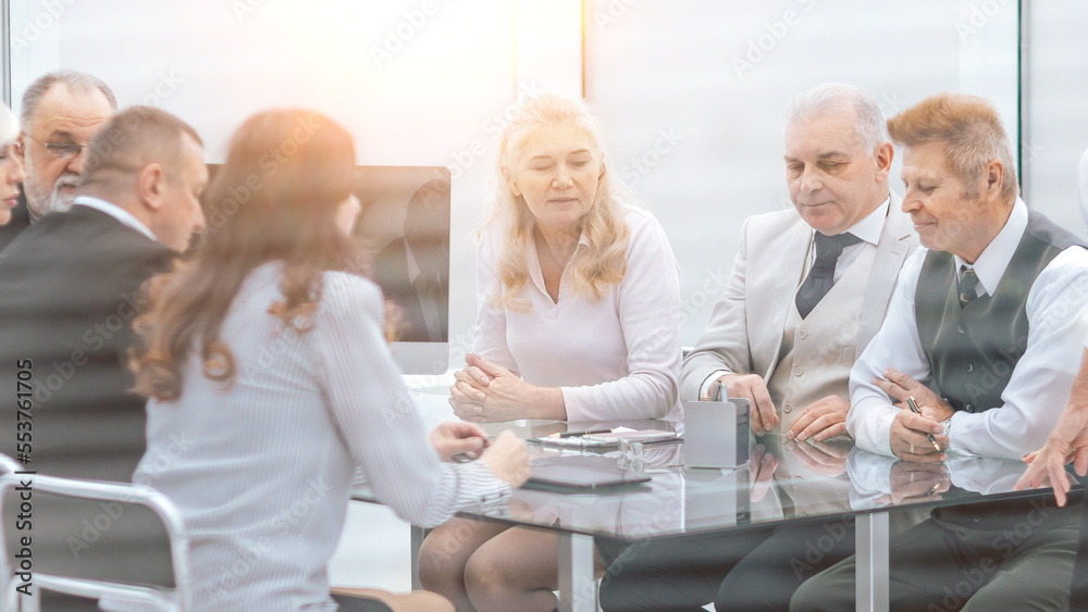group of employees of the company holds a working meeting in the office. communication of partners against the background of sunset group of employees of the company holds a working meeting in the office. communication of partners against the background of sunset
