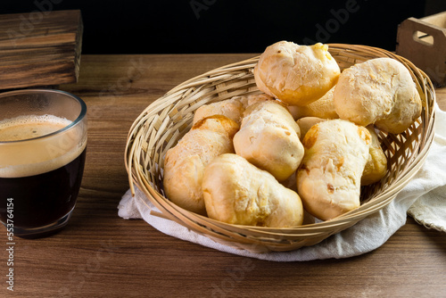 Brazilian Pão de queijo, fresh cheese breads on rustic wood and a hot cup of coffee. Selective focus