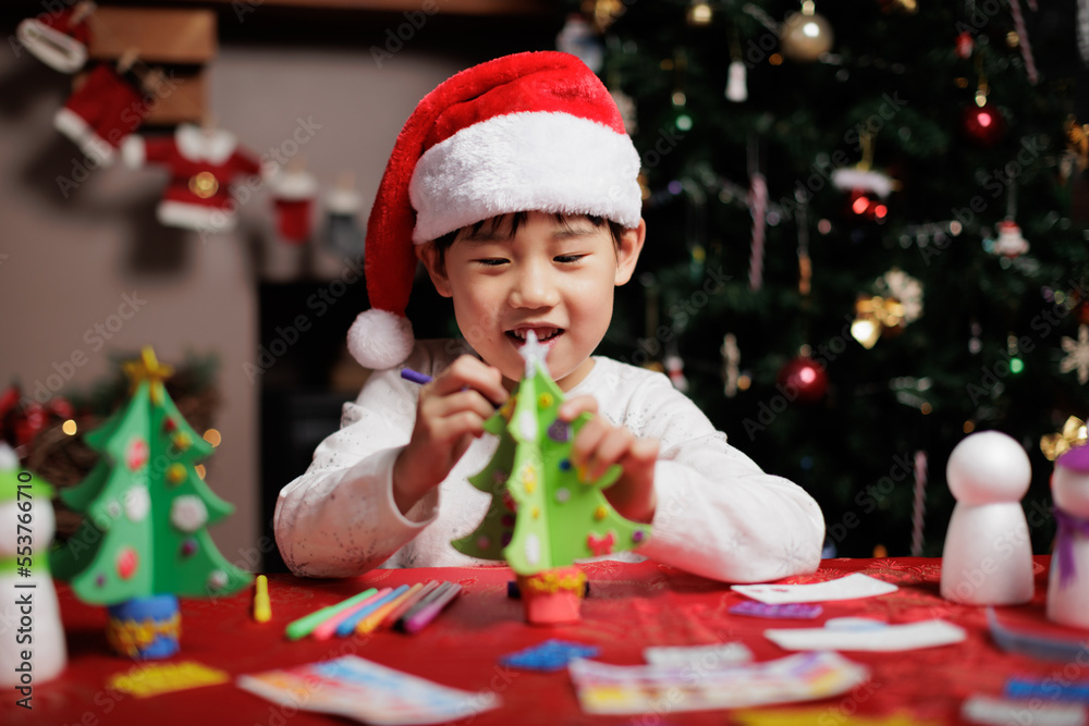 young girl wearing santa hat was making Christmas craft at home young girl wearing santa hat was making Christmas craft at home