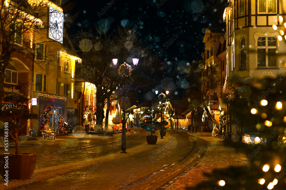 Decorated with Christmas lights, a city street with beautiful houses. Evening city on Christmas Eve with space for a copy