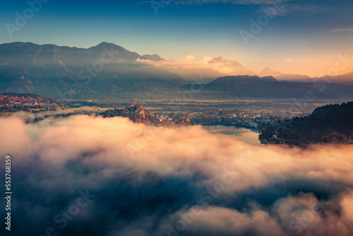 Dramatic autumn sunset on Bled lake. Unbelievable evening view of Bled Castle. Majestic outdoors scene of Julian Alps, Slovenia, Europe. Traveling concept background.