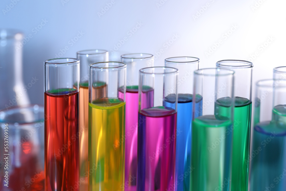 Many test tubes with colorful liquids on blurred background, closeup