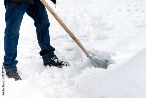 A man cleans snow with a metal shovel