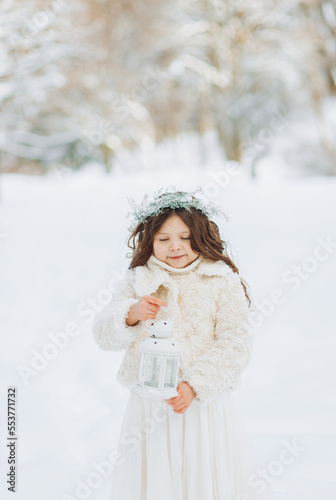 A little girl walks in a snowy park. © Yuliia
