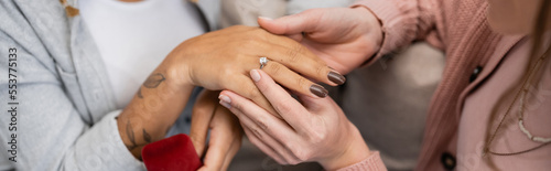 cropped view of lesbian woman wearing engagement ring on finger of african american girlfriend, banner.