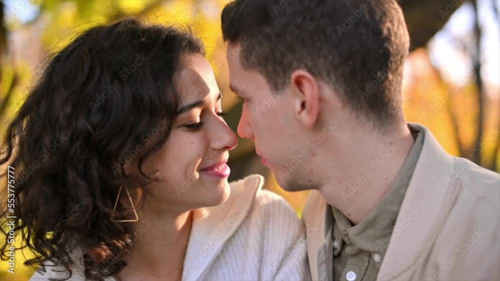 A romantic couple in an autumn park. Man kissing his woman. Autumn atmosphere, yellowed trees and leaves on background. Slow motion A romantic couple in an autumn park. Man kissing his woman. Autumn atmosphere, yellowed trees and leaves on background. Slow motion