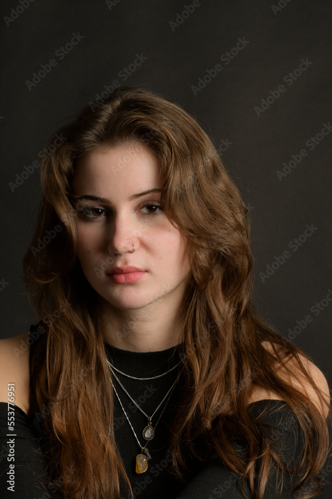 Beautiful tender girl in a black top with beautiful long dark hair. Black background. Beauty, makeup, feelings, emotions, fashion. close portrait