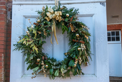 christmas wreath on door with gold ribbon baubles and cinnamon sticks