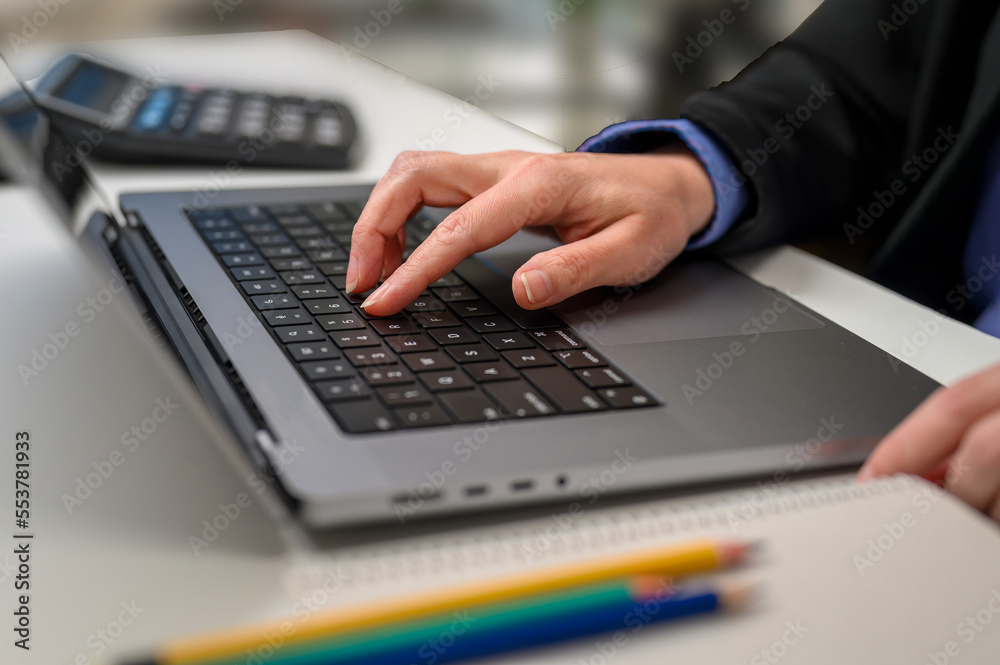 Close-up of a business woman's hand working on a laptop computer on a desk in a home office, freelancer. Close-up of a business woman's hand working on a laptop computer on a desk in a home office, freelancer.