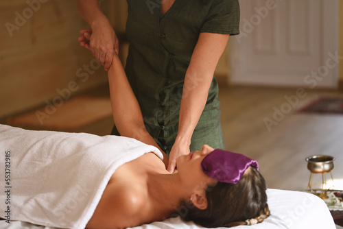 Woman lying down with bag of seeds in her eyes receiving tuina massage. Selective focus