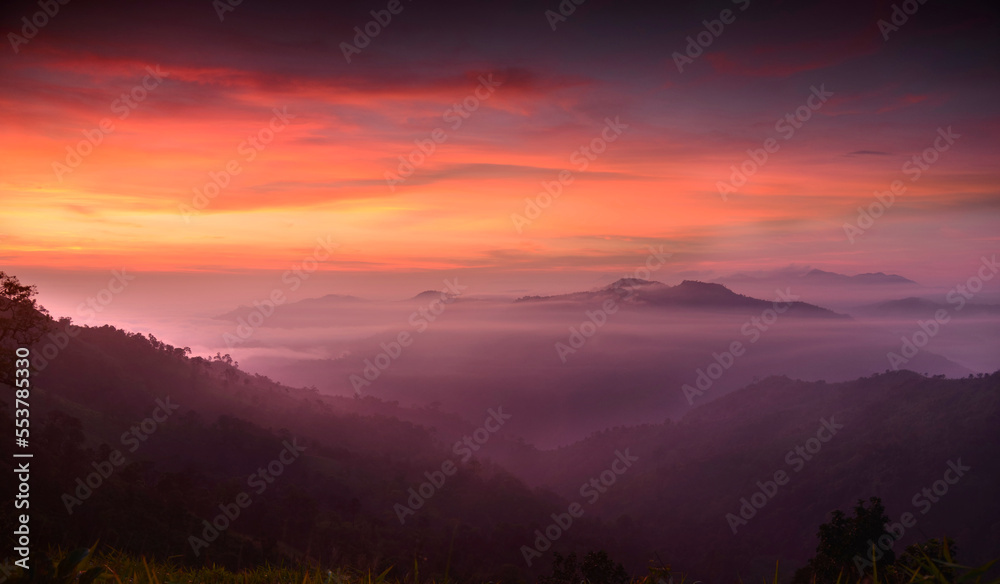 Fluffy fog plane is covering a mountain with colorful twilight sky in sunrise time