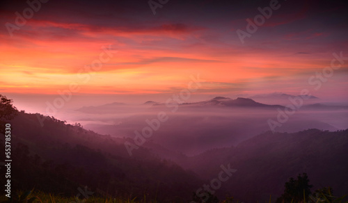 Fluffy fog plane is covering a mountain with colorful twilight sky in sunrise time © Chartchai