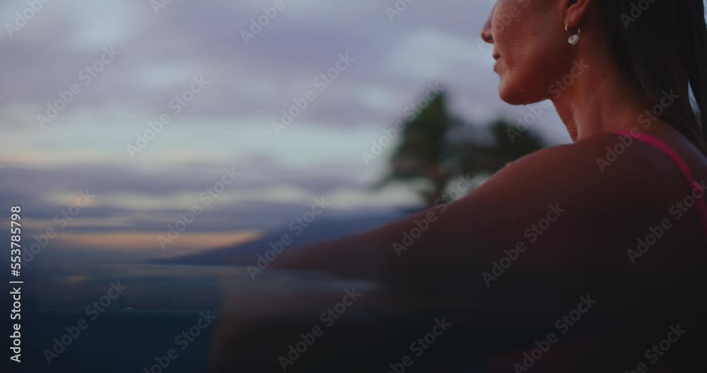 Close up of beautiful young woman relaxing in the pool at tropical resort on vacation, looking out over the ocean at sunset Close up of beautiful young woman relaxing in the pool at tropical resort on vacation, looking out over the ocean at sunset