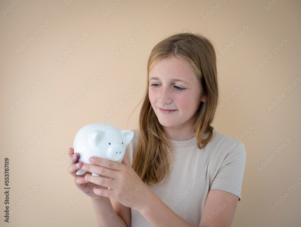 cool young girl in front of brown background holding piggy bank in her hands and wearing brown t-shirt cool young girl in front of brown background holding piggy bank in her hands and wearing brown t-shirt