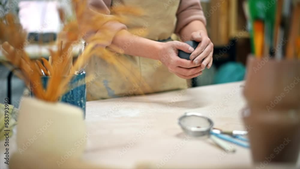 The master of sculpting pottery working in a studio. Kneading a piece of clay with her hands. Tools on the table. Slow motion The master of sculpting pottery working in a studio. Kneading a piece of clay with her hands. Tools on the table. Slow motion