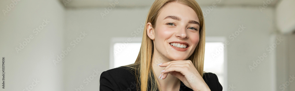 joyful blonde woman with natural makeup and hand near chin looking at camera at home, banner. joyful blonde woman with natural makeup and hand near chin looking at camera at home, banner.