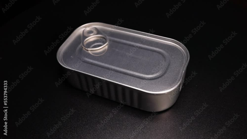 metallic tin can with canned food is spinning on a black background
