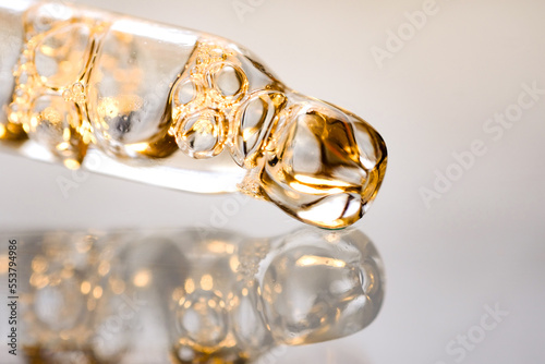 Pipettes with golden serum with air bubbles on light background. Macro photography, side view, space for text.