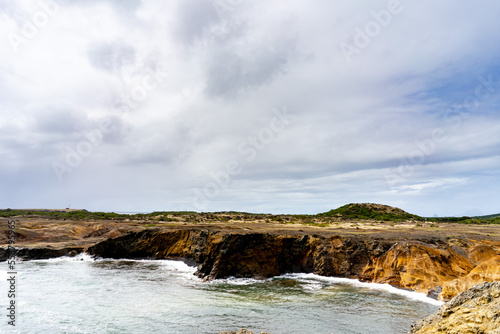 Multicolor sand landscape with ocean and grey sky and clouds