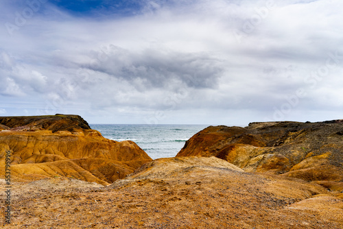 Multicolor sand landscape with ocean and blue sky and clouds