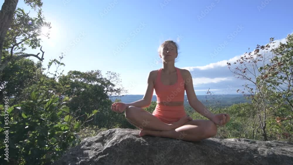 Woman is practicing yoga sitting lotus pose, at a beautiful exotic place on the top of a mountain at sunset. Meditation Woman is practicing yoga sitting lotus pose, at a beautiful exotic place on the top of a mountain at sunset. Meditation