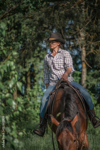 Portrait of a young beautiful girl in a cowboy hat on a horse in the forest. © shymar27