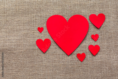 Paper craft hearts on a burlap background top view. Valentine background with many red hearts. Flat lay