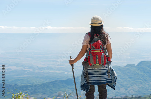 The back of a female tourist Standing looking at the beautiful view on the high mountain. to people travel and backpacker concept.